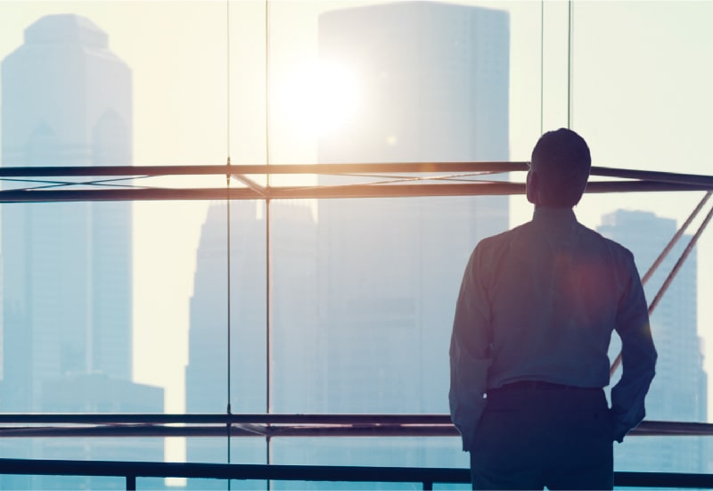 A man contemplates the city below him from a high window