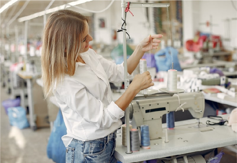 Woman using a sewing machine in an apparel factory