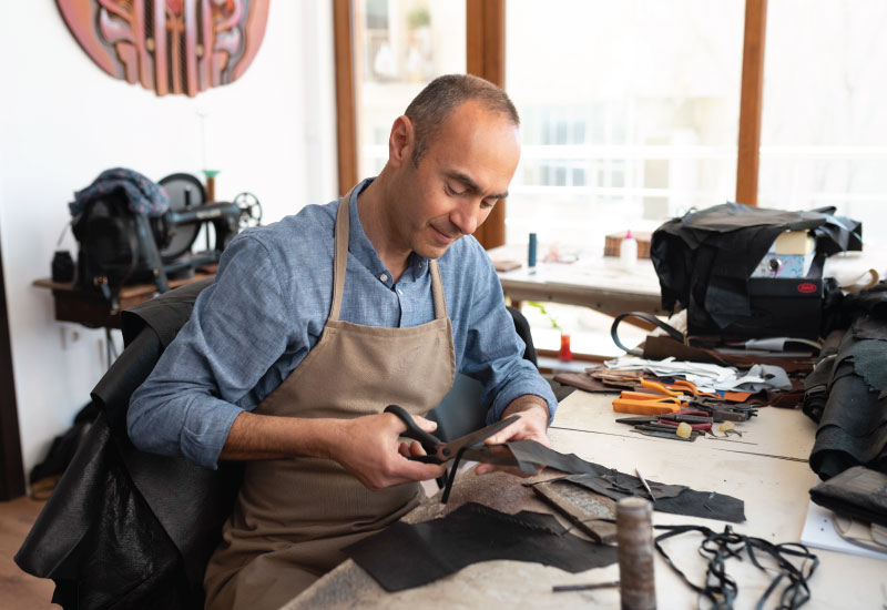 A person is doing cut and sew on a piece of fabric or leather