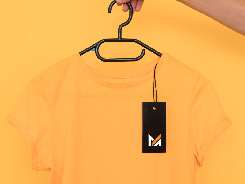 A bright custom yellow t-shirt with a Mega Apparel Logo tag hangs on a black hanger