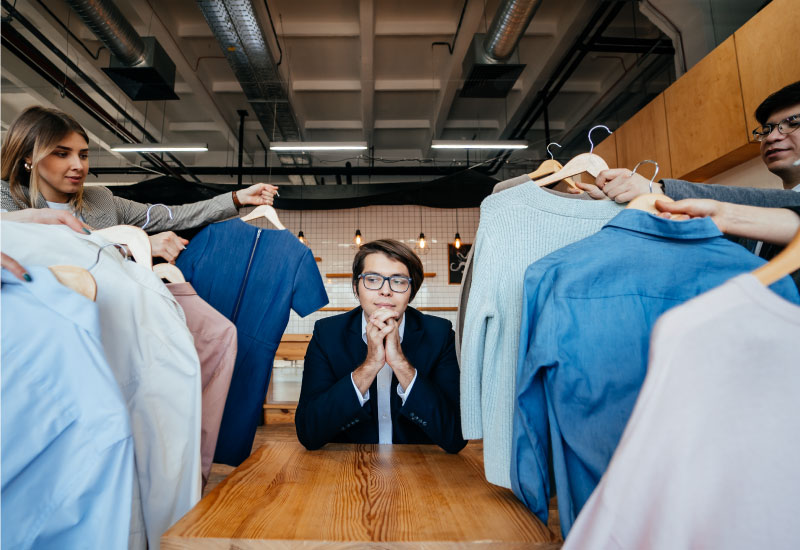 A group of people holding up clothes in a clothing store
